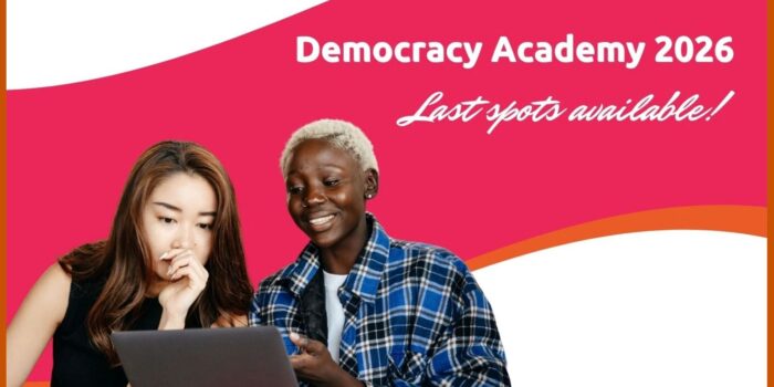 The photos of two young women working together on a laptop in an engaged manner, with the hot pink and orange colors of the academy behind them and the words "Democracy Academy 2026" and "Last spots available" superimposed on the right side.